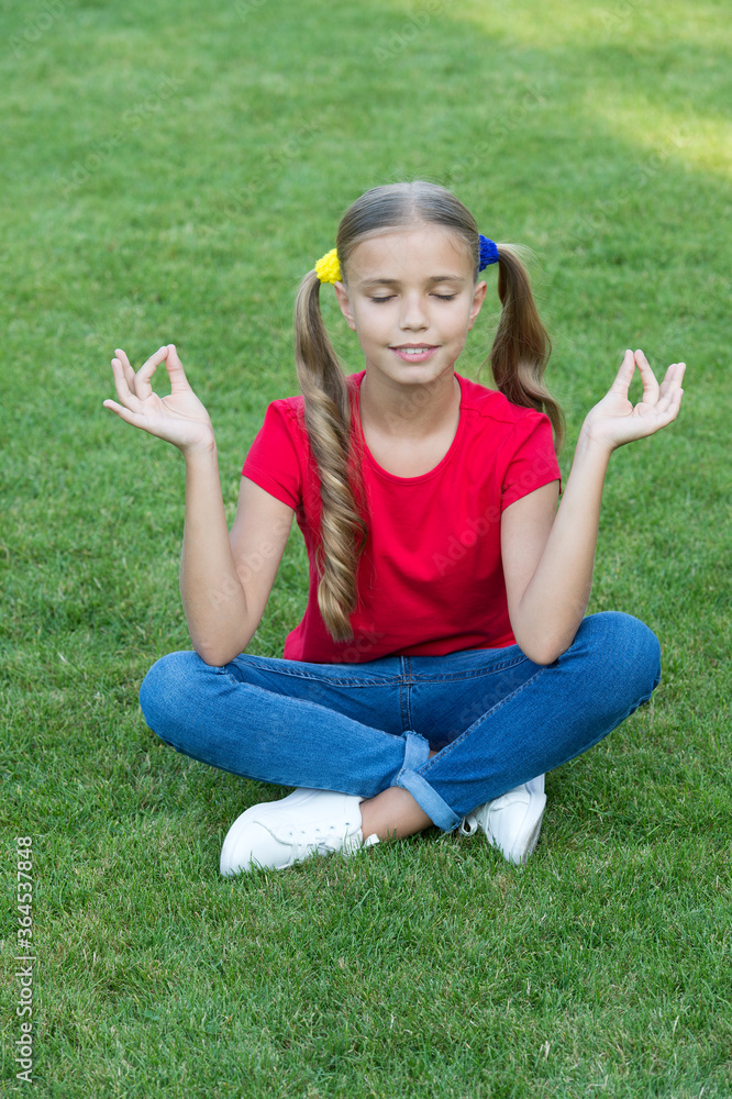 Meditation practice. Little child do meditation on green grass. Small girl sit in mudra position during meditation. Yoga meditation. Zen and enlightenment. Summer vacation. Meditate for concentration Meditation practice. Little child do meditation on green grass. Small girl sit in mudra position during meditation. Yoga meditation. Zen and enlightenment. Summer vacation. Meditate for concentration