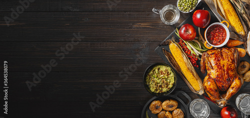 Thanksgiving celebration concept, baked turkey with vegetables on a table with corn, green peas, ripe apples and other vegetables. autumn harvest