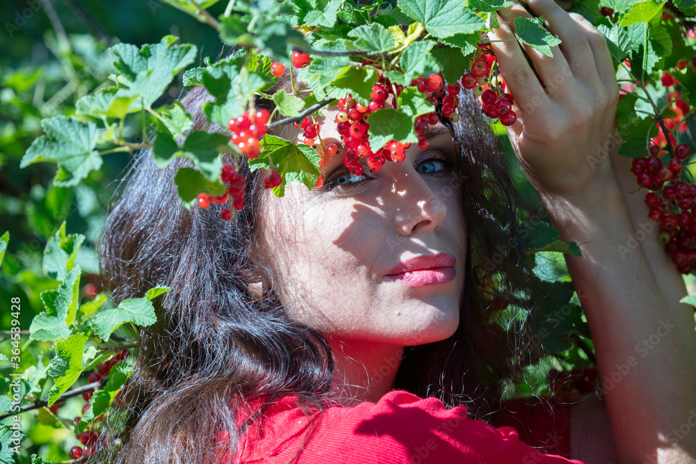 Naklejka premium brunette with long hair, green eyes, in a red dress, red berries, currants