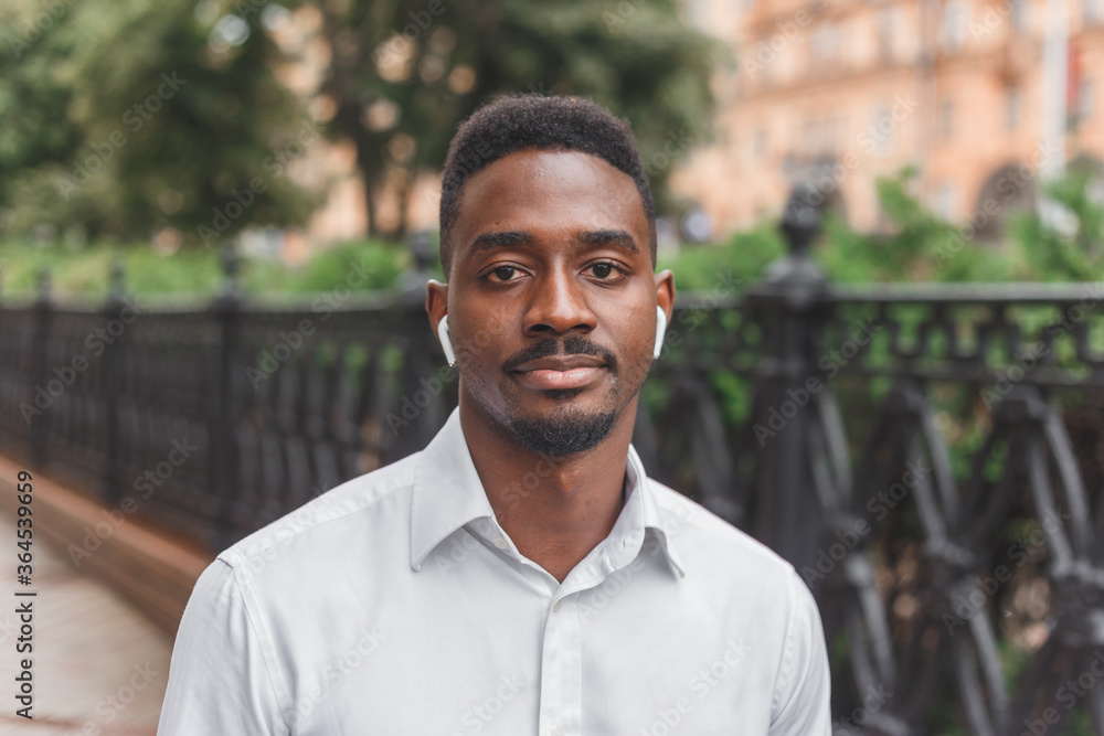 Young black african man in city face portrait with wireless earbuds Young black african man in city face portrait with wireless earbuds