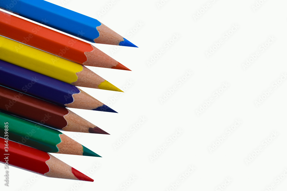 One Line of seven different colored wood pencil crayon places on a white paper One Line of seven different colored wood pencil crayon places on a white paper