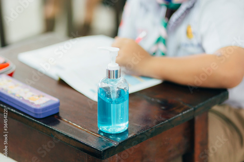 New Normal. COVID-19 prevention and protection in school,Pocket antiseptic hand sanitizer gel on the table in the classroom with students background,hydro alcoholic