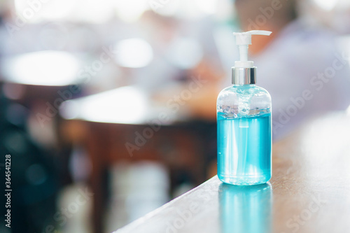 New Normal. COVID-19 prevention and protection in school,Pocket antiseptic hand sanitizer gel on the table with students background
