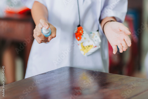 Students spraying alcohol on the table, studying during the coronavirus