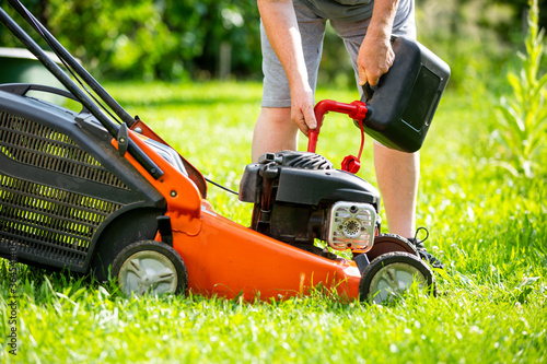 Man refueling the lawnmower on his huge garden, gardening concept