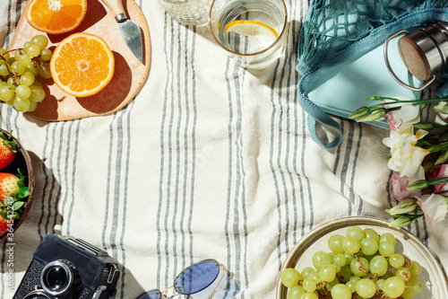 Summer picnic flatlay, fruits, berries and lemon water on striped cotton blanket