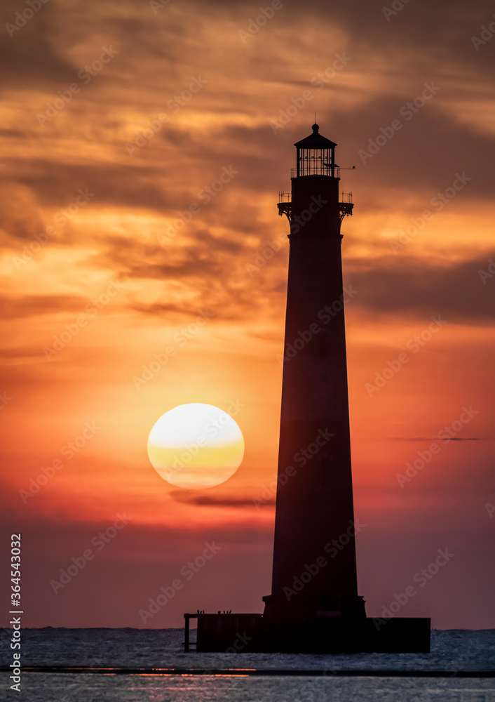 Just after sunrise the sky over the Atlantic Ocean is painted with color silhouetting the historic old Morris Island Lighthouse near Charleston, South Carolina.