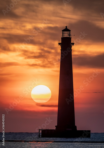 Just after sunrise the sky over the Atlantic Ocean is painted with color silhouetting the historic old Morris Island Lighthouse near Charleston, South Carolina.
