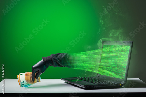 Foto A computer hacker is stealing money from a monitor screen