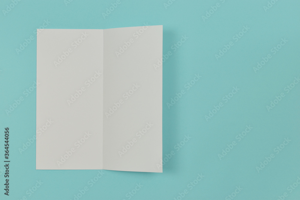 Two folded blank paper leaflet on blue background. Two folded blank paper leaflet on blue background.