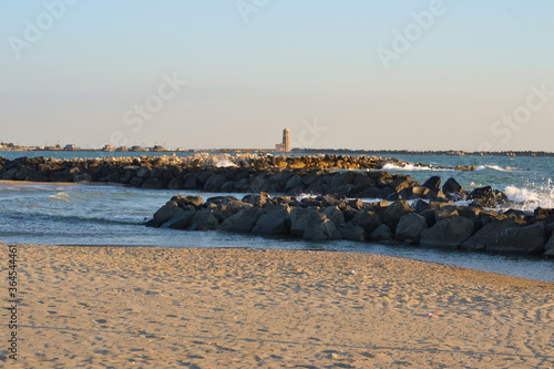 view of port and old light house fiumicino, Italy from the beach in the evening showing wave breakers