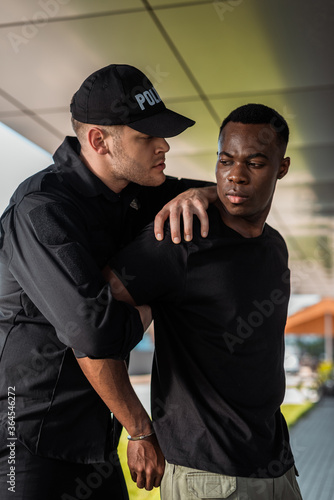 angry police officer in uniform detaining african american man suffering from pain, racism concept © LIGHTFIELD STUDIOS