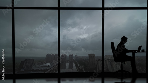 The man is working at the table near the windows in the business center