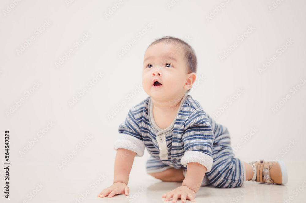 Smiling crawling asian baby boy at home on floor with white background. Smiling crawling asian baby boy at home on floor with white background.
