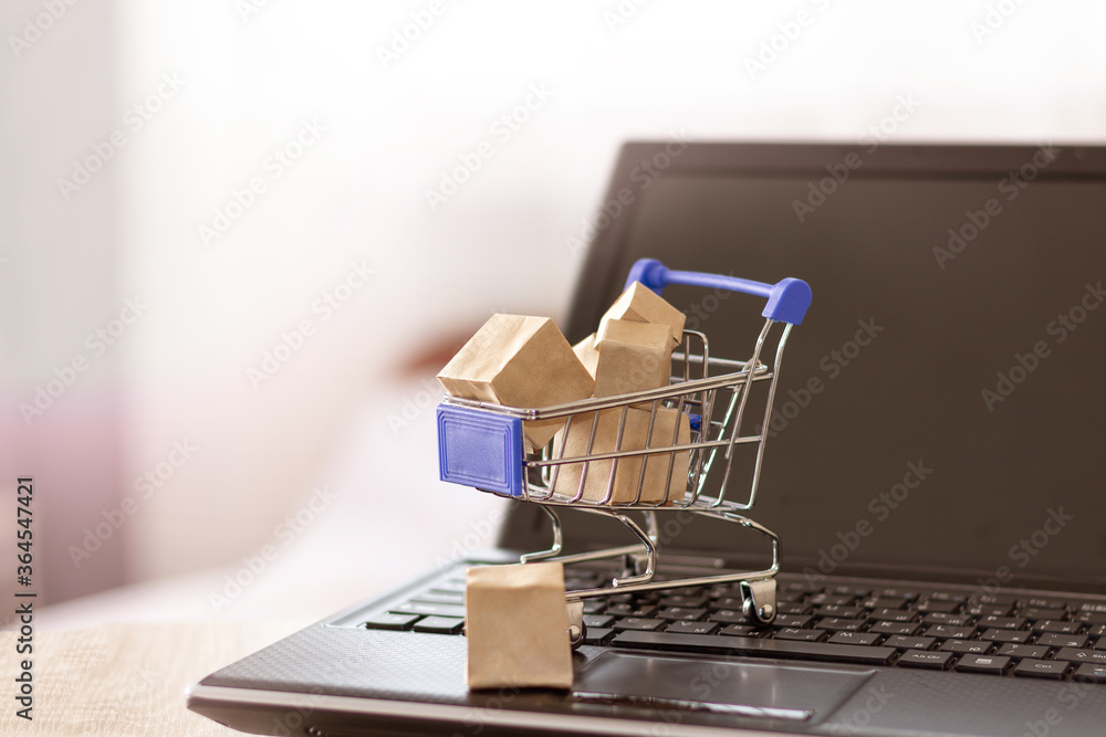 Shopping basket and boxes on laptop keyboard. Online shopping with home delivery.