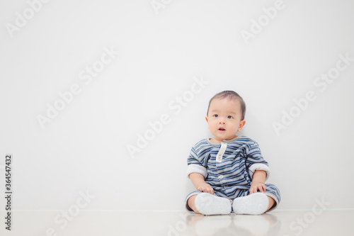 Smiling sitting asian baby boy at home on floor with white background.