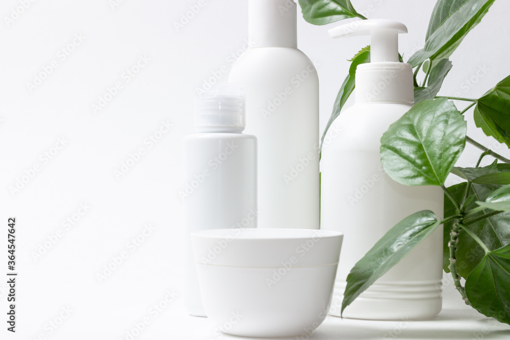 Set of cosmetic cans of organic cosmetics for face and body care on a white background with green leaves. Cream, shampoo and lotion on a light background. Layout, copy space. Set of cosmetic cans of organic cosmetics for face and body care on a white background with green leaves. Cream, shampoo and lotion on a light background. Layout, copy space.