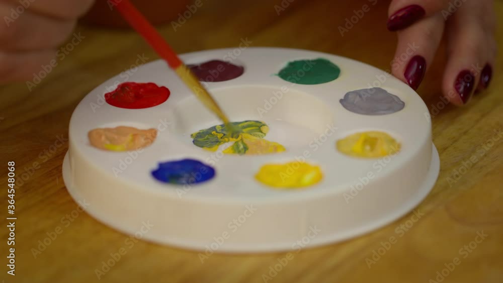 Close up view of mixing yellow and blue colors of paints on palette on desk in art painting studio. Painter, drawing hobby, inspiration, coloring, creating new shades, artist's workshop concept Close up view of mixing yellow and blue colors of paints on palette on desk in art painting studio. Painter, drawing hobby, inspiration, coloring, creating new shades, artist's workshop concept