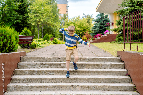 Portrait of a schoolchild with backpack leaping . the boy runs a backpack around the school yard.Childhood, education learning concept