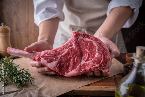 butcher serving fresh tomahawk steak meat to customer photo