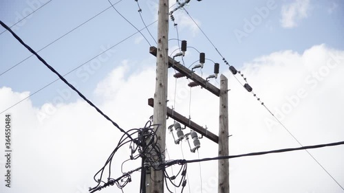 Overhead Electric Power Transmission Lines Under A Cloudy Blue Sky - Tilt-Up Shot