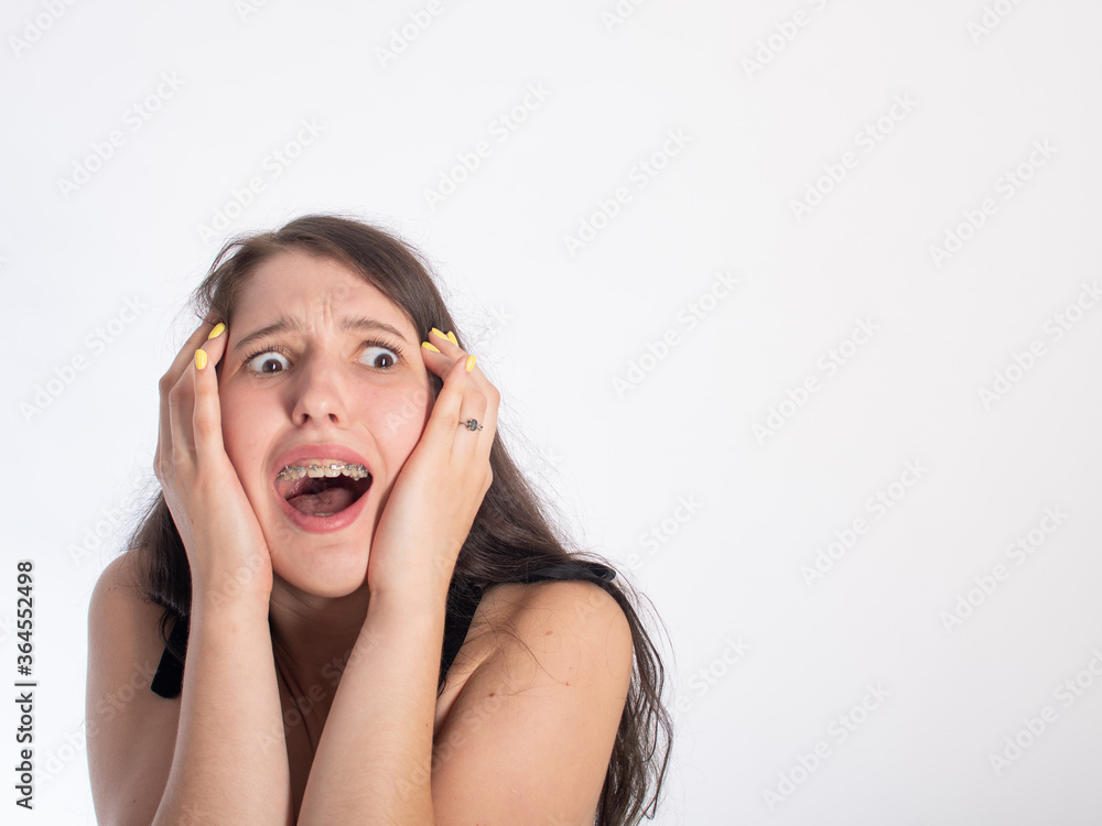 portrait of a young pretty black-haired girl on a white background. on the girl's face is an emotion of fright/horror. isolate on a white background. space for text. portrait of a young pretty black-haired girl on a white background. on the girl's face is an emotion of fright/horror. isolate on a white background. space for text.