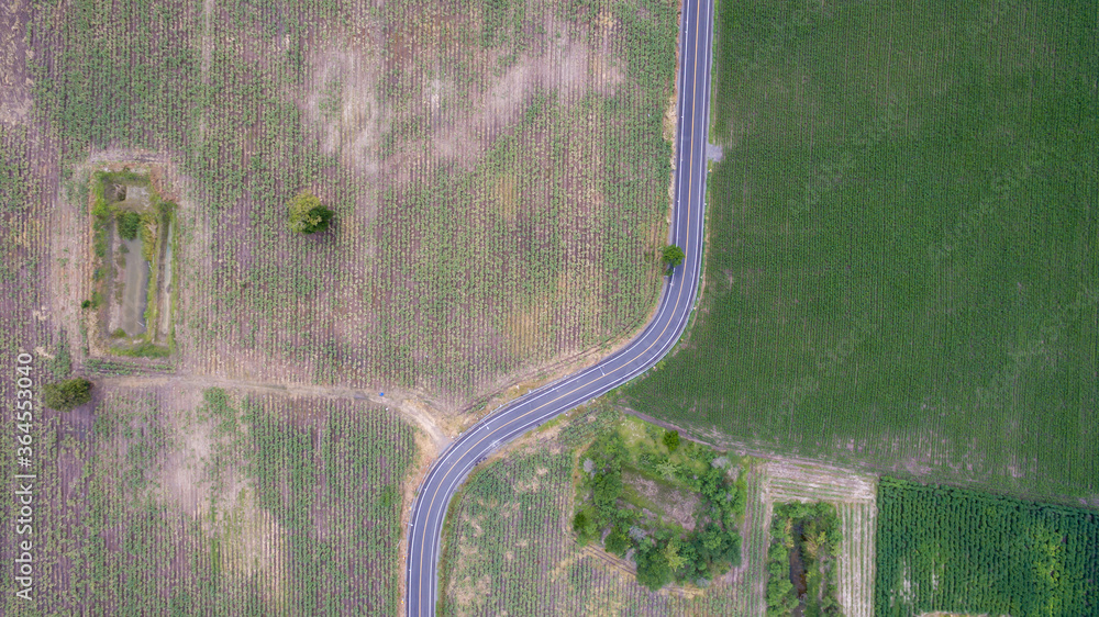 Aerial view road curve construction. Aerial above view of a rural landscape with a curvy road running through. Aerial view of curving road through colorful spring agriculture fields. - obrazy, fototapety, plakaty 