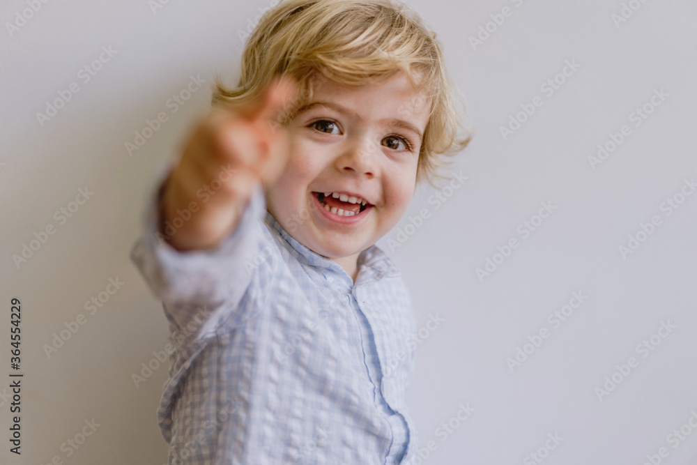 Adorable little kid wearing casual shirt smiling and looking at camera on white background of studio Adorable little kid wearing casual shirt smiling and looking at camera on white background of studio