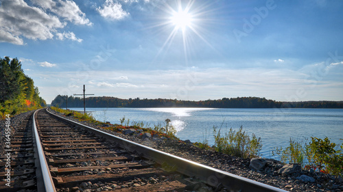 Railroad tracks with beautiful blue sky with clouds, lake