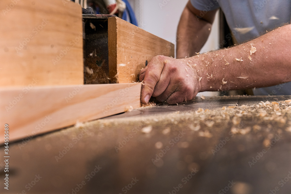 Low angle of closeup unrecognizable carpentry master milling timber using modern electric machine in light contemporary workshop Low angle of closeup unrecognizable carpentry master milling timber using modern electric machine in light contemporary workshop