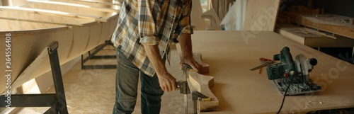 Caucasian male using electric circular saw to make a canoe paddle in his workshop. Boat making hobby, small business owner