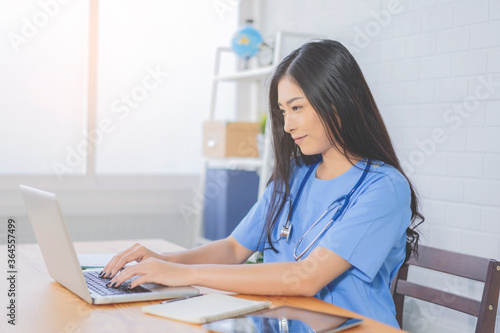 Isolation professional female Asian doctor working on laptop in a hospital clinic, Doctor working on desk computer tablet paperwork in the office.pandemic infection outbreak Coronavirus Medical