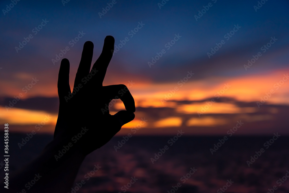 ok sign shown by hand on sunset background ok sign shown by hand on sunset background