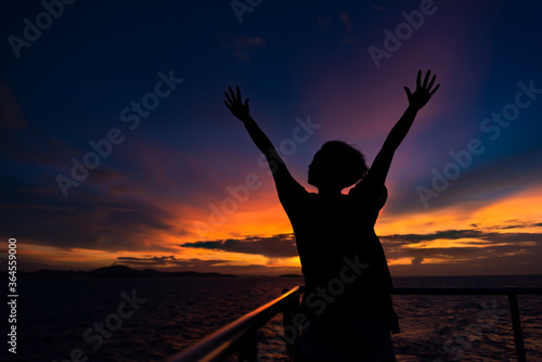 silhouette of a girl with hands up. on sunset background