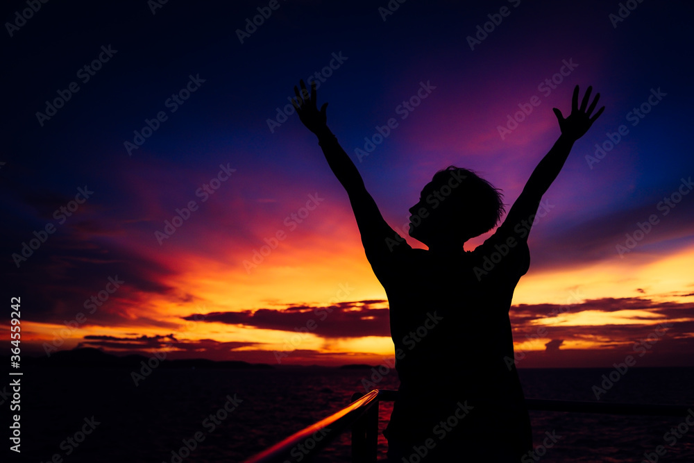 silhouette of a girl with hands up. on sunset background