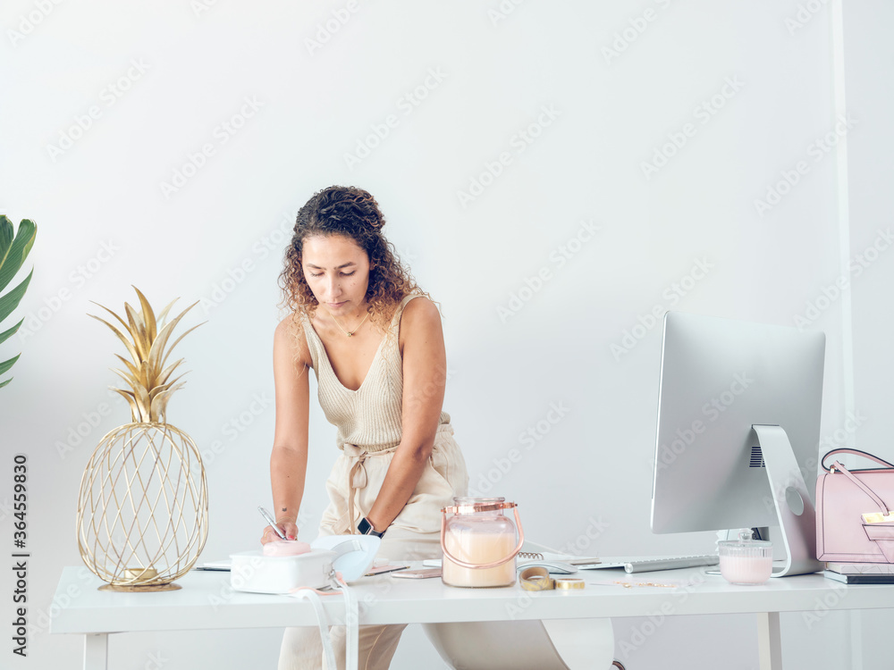 Charming young female in stylish elegant outfit standing near office desk and writing Charming young female in stylish elegant outfit standing near office desk and writing