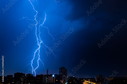 Bright flash of powerful lightning in the city at nighttime.