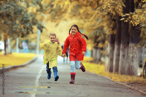 children run in the yellow autumn park rain / fun walk autumn seasonal landscape weather wet