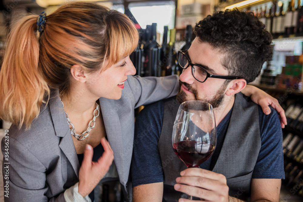 Man and woman sharing red wine in glass having degustation in market wine house. Man and woman sharing red wine in glass having degustation in market wine house.