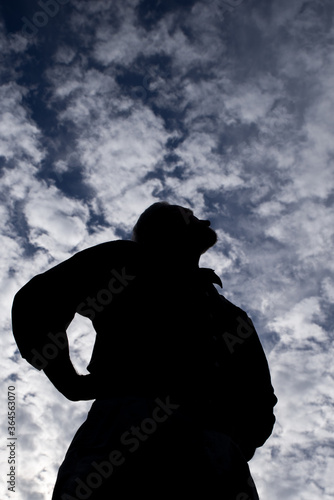 Male silhouette looking up satisfied and with pride, admiring contemplating thinking taking in the beauty of the cloud filled sky, defiant, challenging