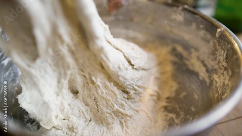 close up girl hands folding bread dough in metal bowl photo