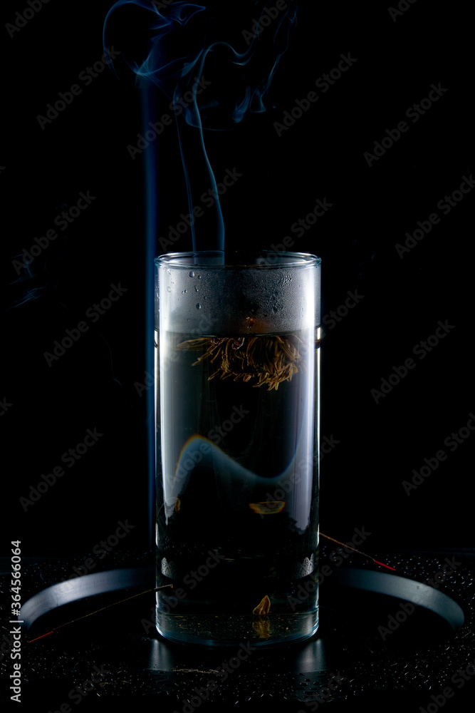 Brewing Chinese tea from a flower in a glass flask on a background of incense smoke Brewing Chinese tea from a flower in a glass flask on a background of incense smoke