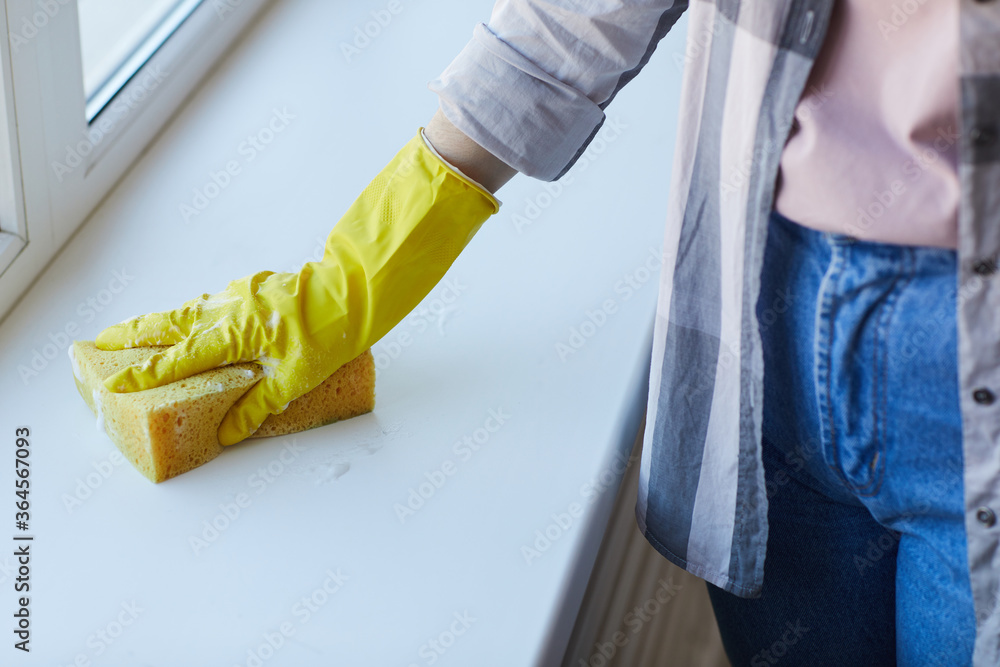 Close-up of woman doing chores she wearing rubber gloves and using sponge to clean