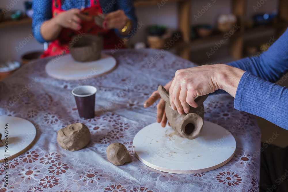 Fototapeta premium Pottery class and workshop: people making clay mugs in pottery studio. Handmade, art and study concept