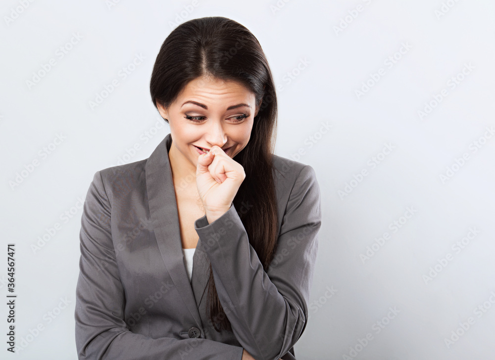 Beautiful smiling business woman in suit holding the hands under the face and looking up on blue background. Closeup Beautiful smiling business woman in suit holding the hands under the face and looking up on blue background. Closeup