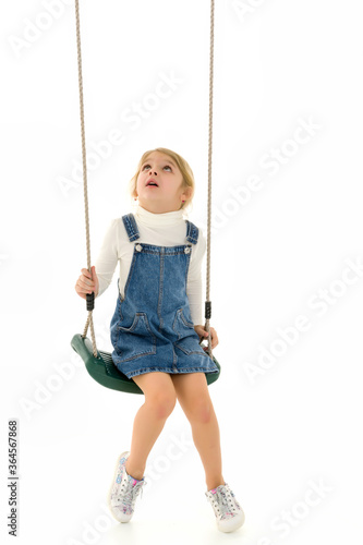 Cute Happy Girl Sitting on Rope Swing and Looking Up