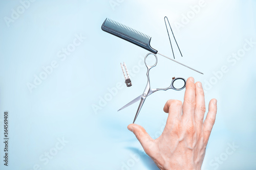 Had holding flying hairdresser tools comb, scissors under trendy color background with copy space and soft light. Stylish Professional Barber Scissors, Hairdresser salon concept, Haircut accessories.