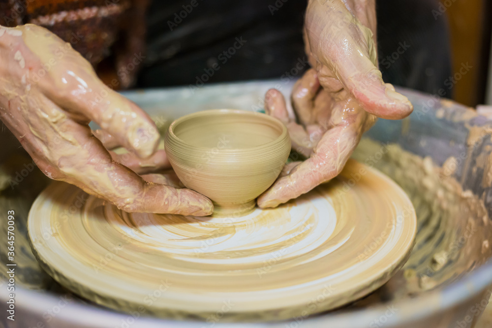 Close up view - professional male potter making mug in pottery workshop, studio. Handmade, small business, crafting work concept