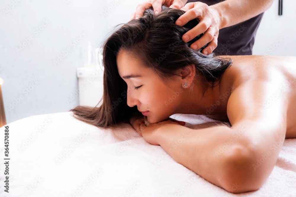 Fototapeta premium Head massage. Indian head massage. Spa treatments. Photo of a young woman in a massage therapist’s office.