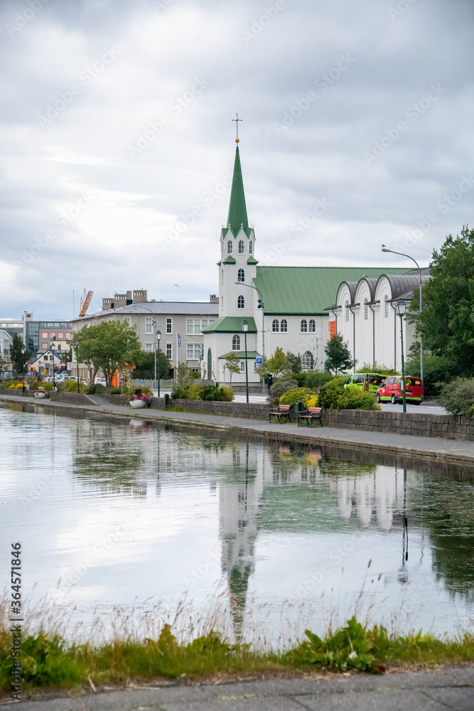 REYKJAVIK, ICELAND - AUGUST 11, 2019: Lake Tjornin with church on a cloudy summer day